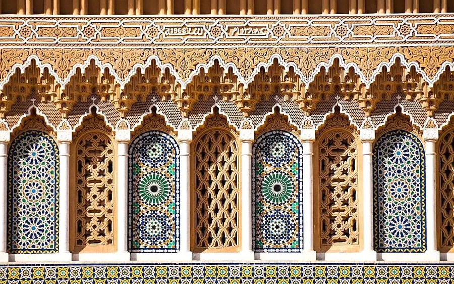 Zellige mosaic and carved stucco on a row of Moroccan arches