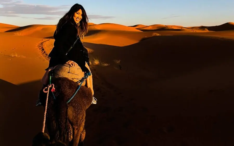 A traveller riding a camel over the dunes at golden hour