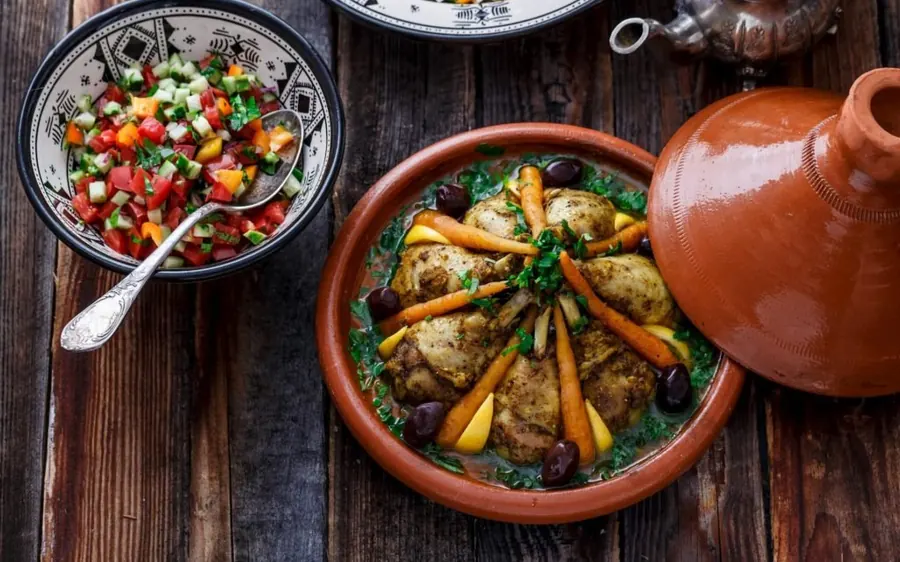 A chicken tagine with olives beside its clay pot