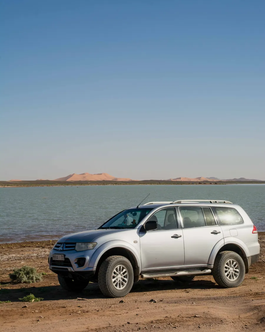 4x4 vehicle parked beside a seasonal lake near the Merzouga dunes