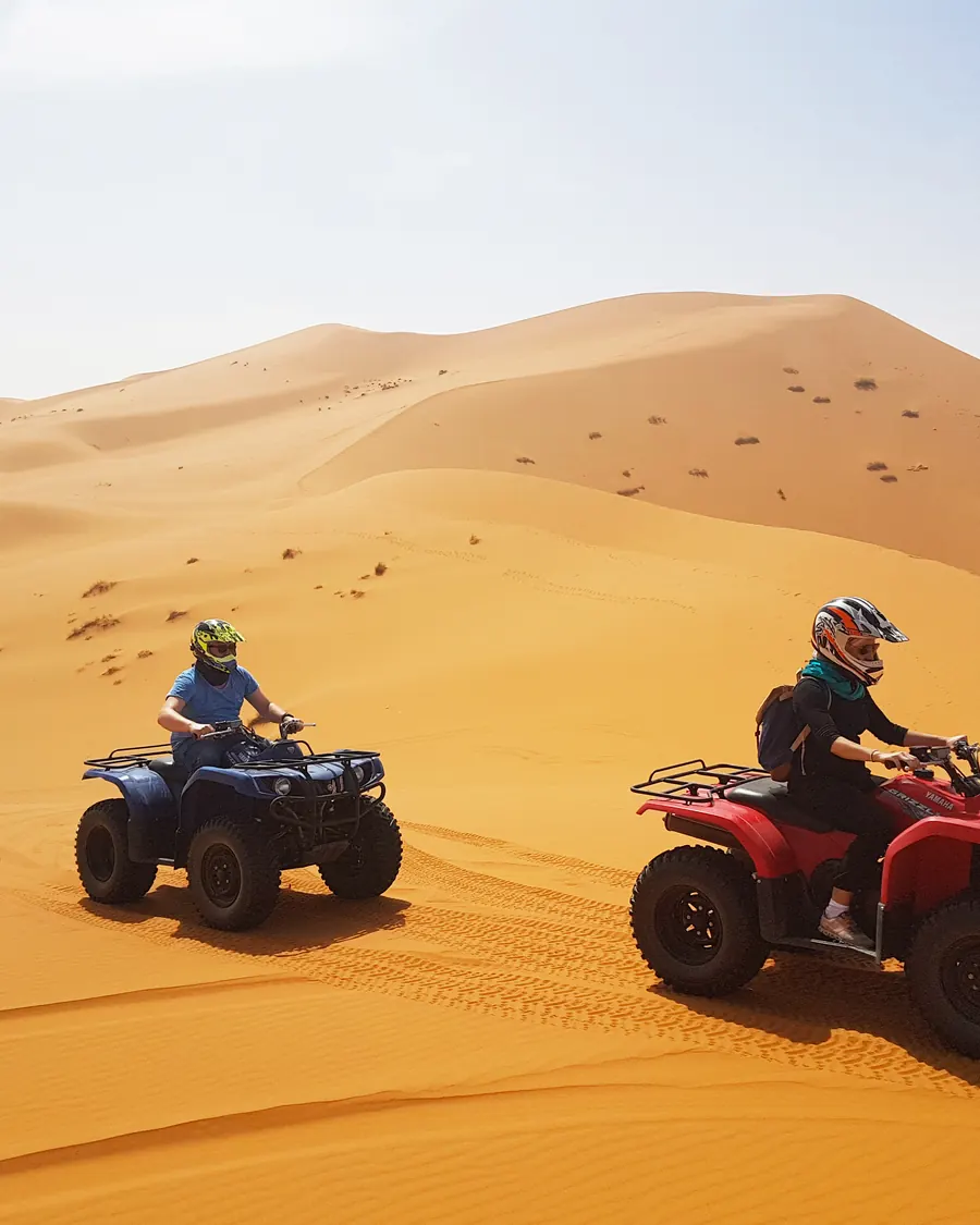 Two quad bikes riding across the Erg Chebbi dunes