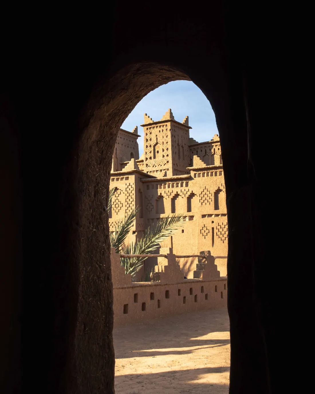 A kasbah tower seen through a shaded earthen archway in southern Morocco