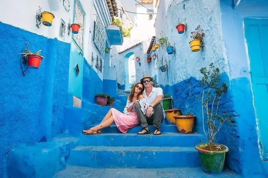 A couple sitting on blue steps in Chefchaouen