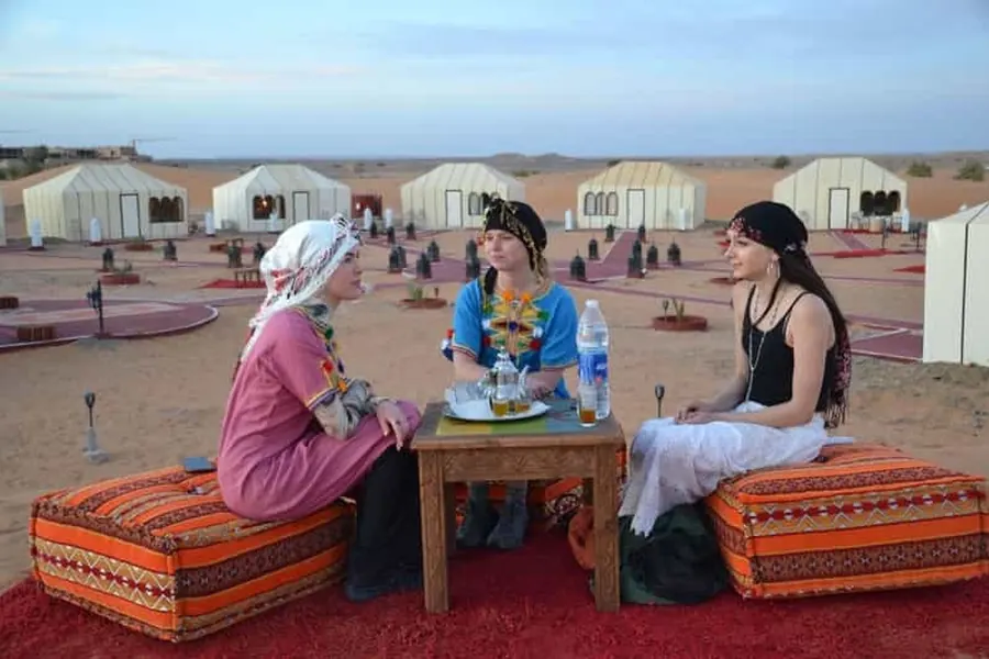 Travellers in scarves sharing tea at a desert camp