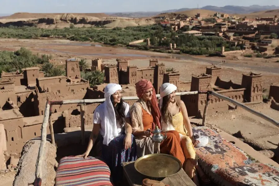 Travellers sharing tea on a terrace above a kasbah village