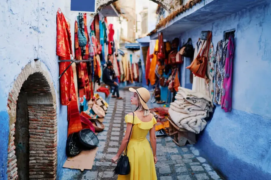 A woman in a yellow dress browsing a shop in the blue lanes of Chefchaouen